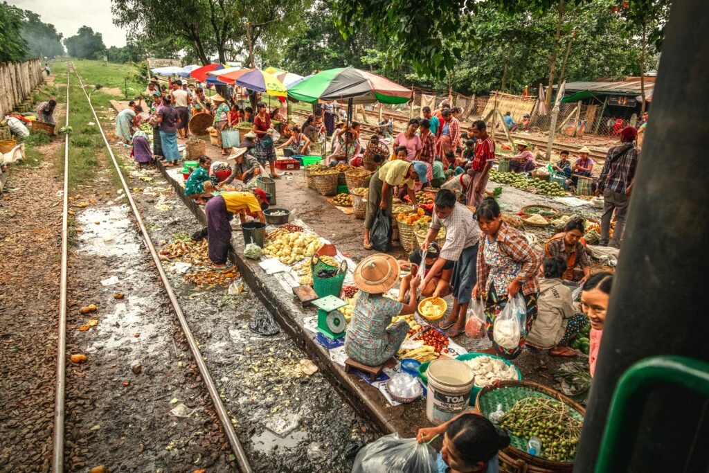 Bustling street market by railway in Yangon, Myanmar, showcasing local culture and commerce.