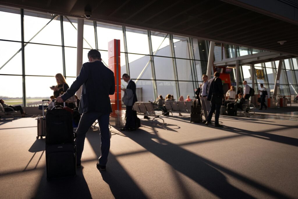 Travelers in a bustling airport terminal with carry-on luggage waiting for departure.