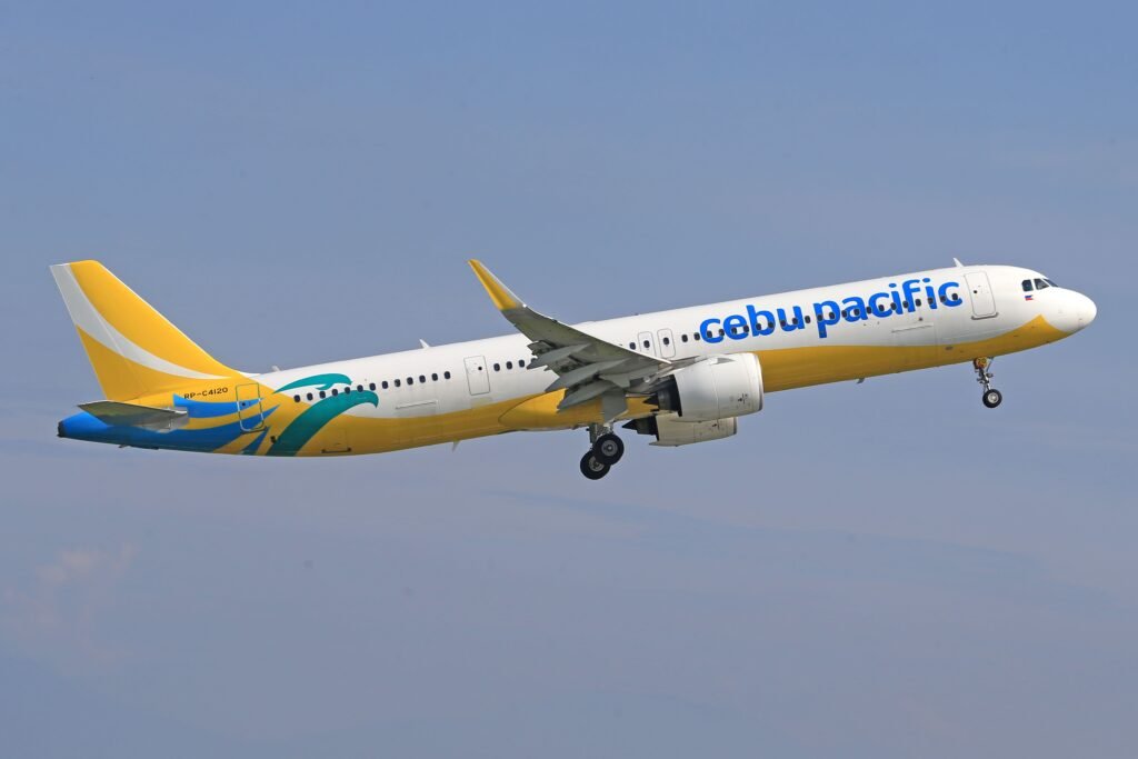 Cebu Pacific aircraft flying against a clear blue sky, showcasing the airline's distinct branding.
