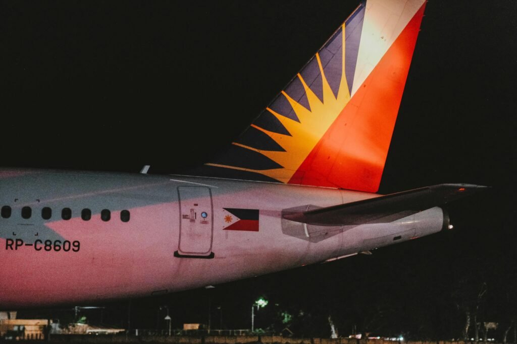 Philippine Airlines aircraft tail fin lit at night on the runway.